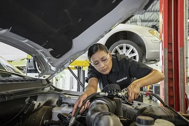 Woman working under the hood of a vehicle